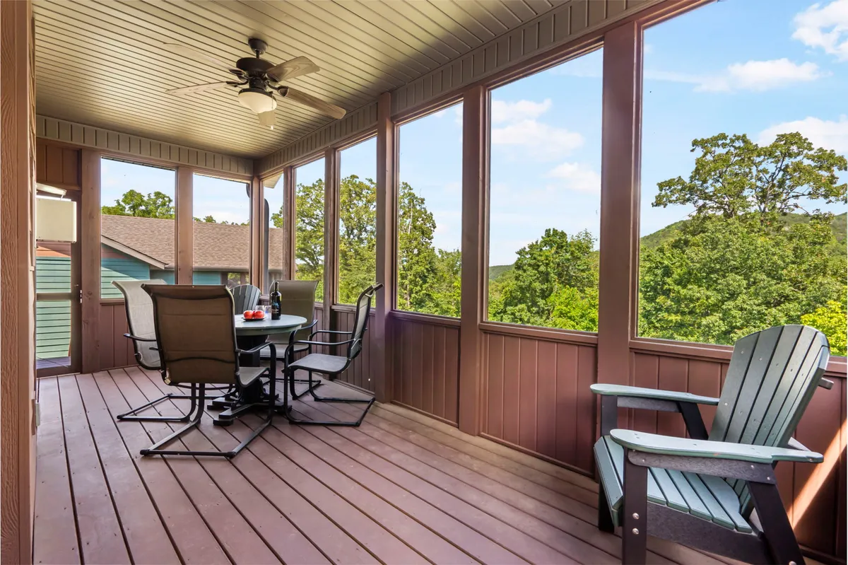 A tranquil screened-in porch featuring a dining table and an Adirondack chair, with greenery visible through the screens. The space feels airy and connected to the outdoors, inviting guests to relax, dine, or read while enjoying valley views and fresh breezes.