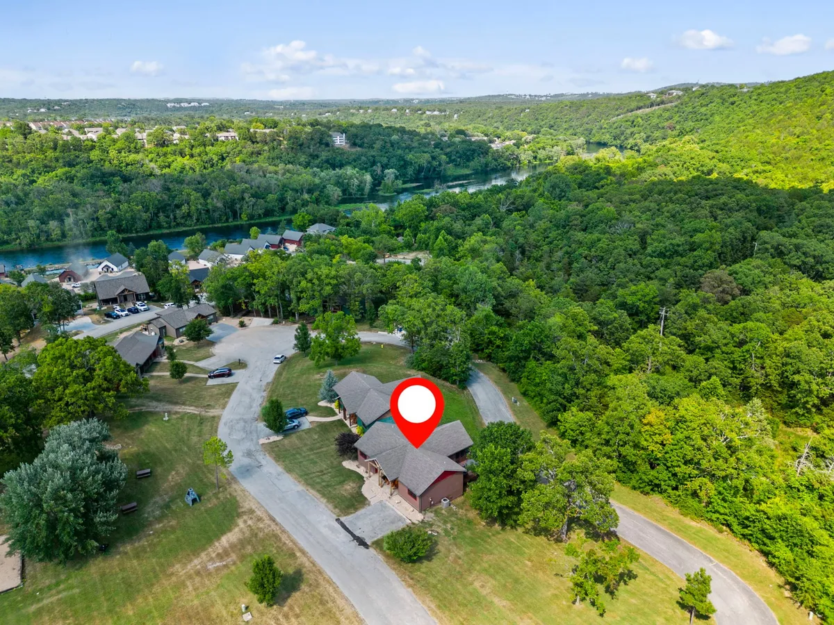 This image features the property nestled among trees with the river clearly visible in the background. The natural setting emphasizes direct access to waterfront activities and scenic views, illustrating the eco-focused, adventure-ready location of Riverhaven.