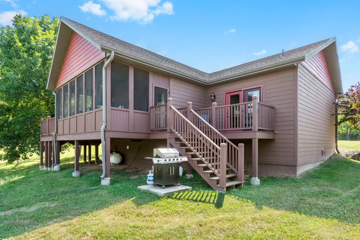 A welcoming screened porch with a staircase and grill, arranged for outdoor dining and gatherings. The setting is ideal for shared meals, board games, or sunset celebrations with loved ones, all while remaining sheltered in comfort.