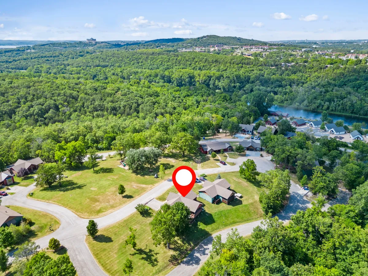 A broad view over green landscapes, residential buildings, and winding roads framed by trees. The image communicates a sense of spaciousness, tranquility, and access to walking or cycling routes—perfect for guests looking to enjoy biking, hiking, or family gatherings outdoors.