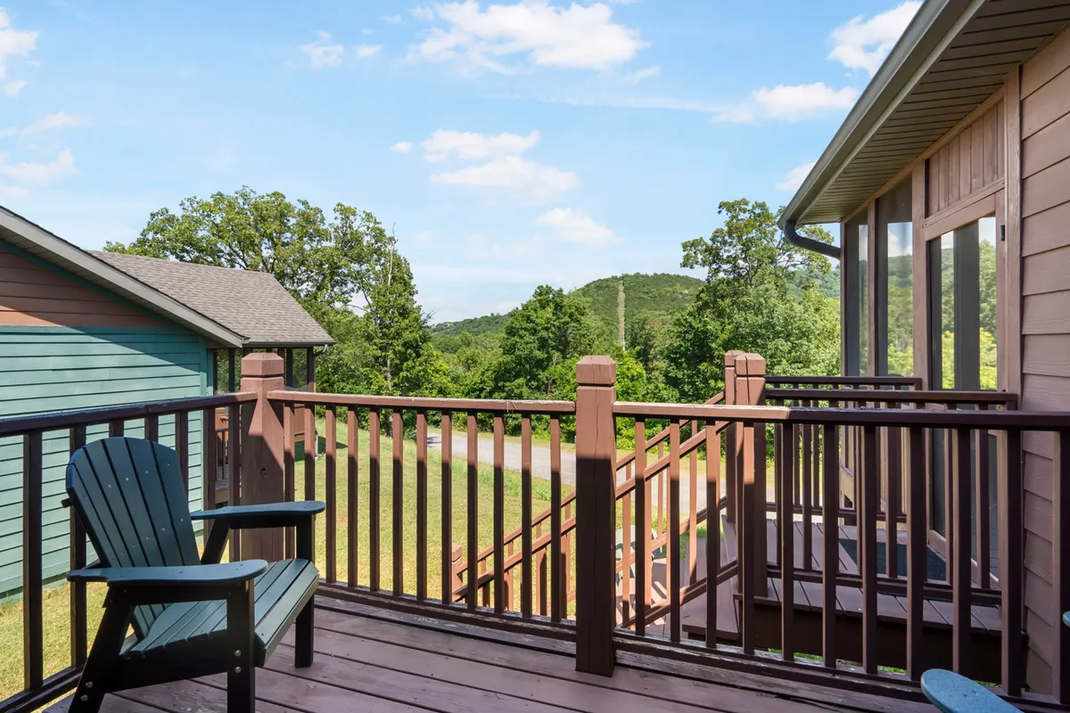 A serene deck with an Adirondack chair overlooking distant hills and lush greenery. The relaxed setting is ideal for sipping morning coffee or unwinding together while soaking in panoramic views and peaceful surroundings.