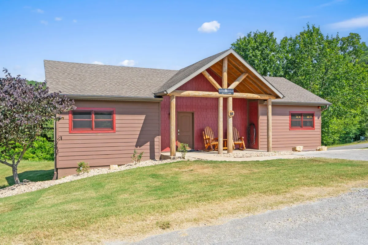 A welcoming front entrance with wooden beams, rocking chairs on the porch, and a landscaped yard. The porch offers a secure outdoor area for both guests and their pets to relax after a day of adventure.
