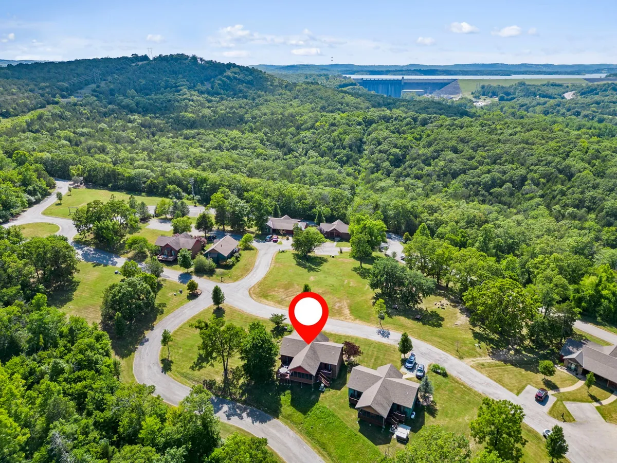 An aerial view highlighting the house surrounded by greenery, nearby nature trails, and peaceful hills in the distance. The setting conveys a sense of space and exploration, ideal for walks and adventures with a small dog.
