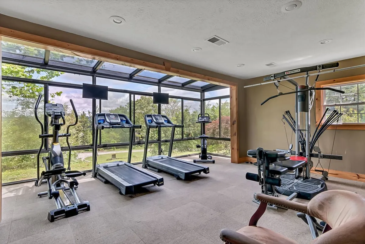 A bright and modern fitness center is shown here, equipped with treadmills, an elliptical machine, weight training equipment, and large windows that let in natural light. The setup invites guests to stay active while enjoying views of the surrounding area.